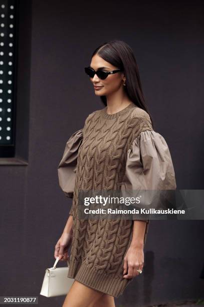 Guest wears a brown knitted dress with puffy sleeves, sunglasses and a white bag outside Max Mara during the Milan Fashion Week - Womenswear...