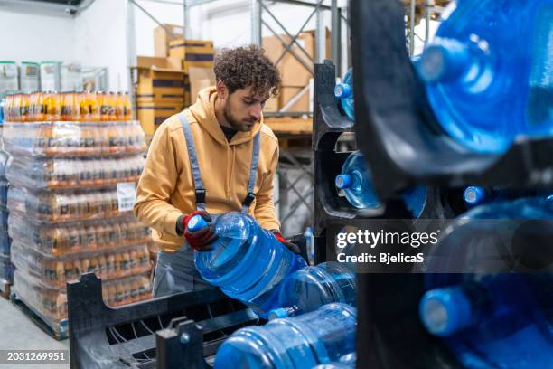 man working at warehouse, carrying water bottles - gallon stock pictures, royalty-free photos & images