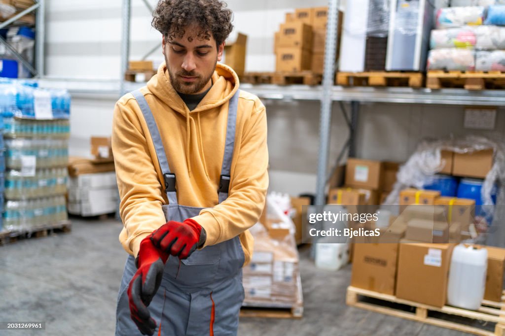 Warehouse worker getting ready for work, putting on protective gloves