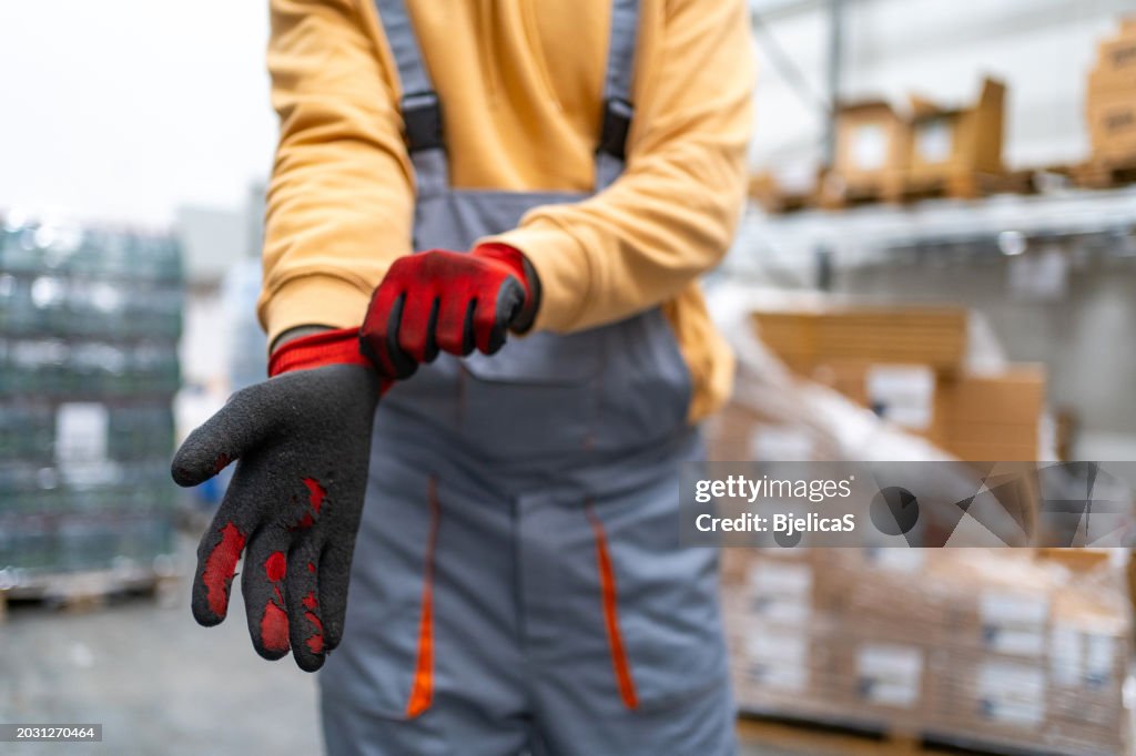 Close up shot of an unrecognisable man putting on protective work gloves at warehouse