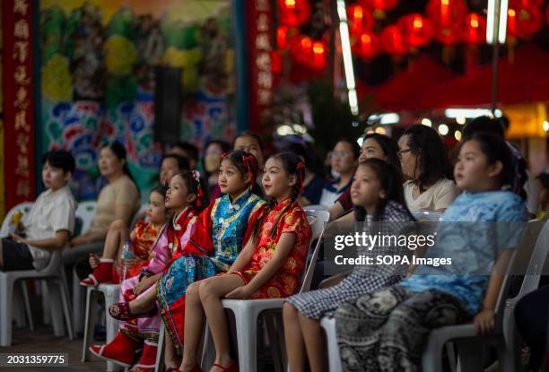 Children watch the Chinese opera performance during the birthday celebration of Godfather Pung Tao Kong festival in Chiang Mai. The Chinese Opera is...