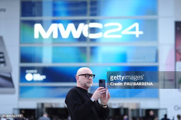 Visitor takes a picture with his smartphone prior entering the Mobile World Congress , the telecom industry's biggest annual gathering, in Barcelona...
