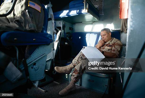 General Colin Powell, Chairman of the Joint Chiefs of Staff, reads while en route to the USS Wasp, off the coast of Somalia, April 1993.