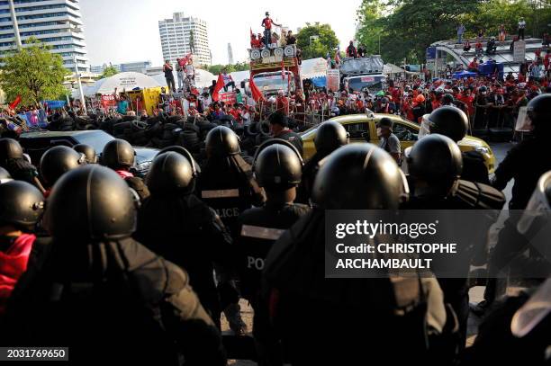 Riot policemen stand-off with 'Red Shirt' anti-government protesters entrenched in their fortified camp behind a barricade at the Silom road...
