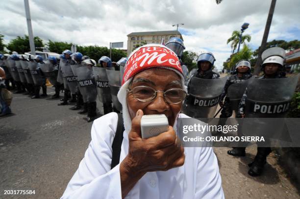 National Police agents look at a supporter of ousted Honduran President Manuel Zelaya outside the hotel where the head of the Organization of...