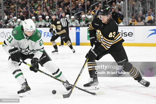 Danton Heinen of the Boston Bruins passes the puck in front of Jason Robertson of the Dallas Stars during the first period at the TD Garden on...