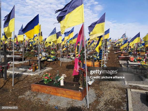 February 2024, Ukraine, Charkiw: Ukrainian flags fly over the graves of fallen soldiers at the cemetery. According to President Selensky 000...