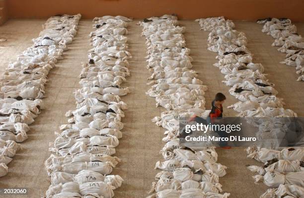 An Iraqi child jumps over a line of remains in a school where bodies have been brought from a mass grave discovered in the desert in the outskirts of...