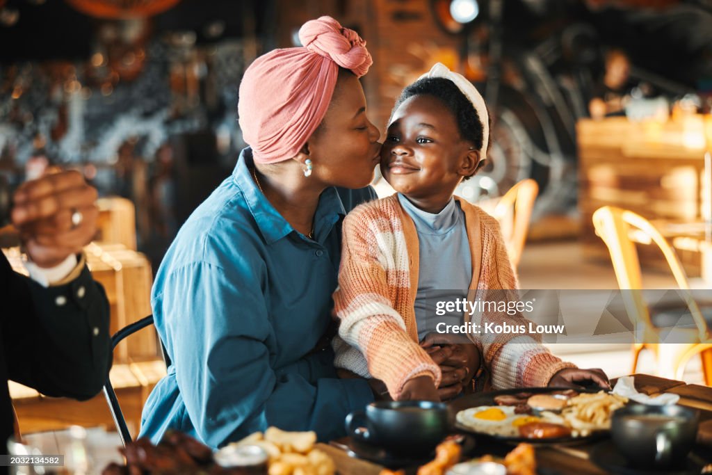 Black family, restaurant and eating with mom kiss and child together with bonding, food and care. Love, diner and table with burgers and happy girl with lunch and hungry people in a cafe with drink