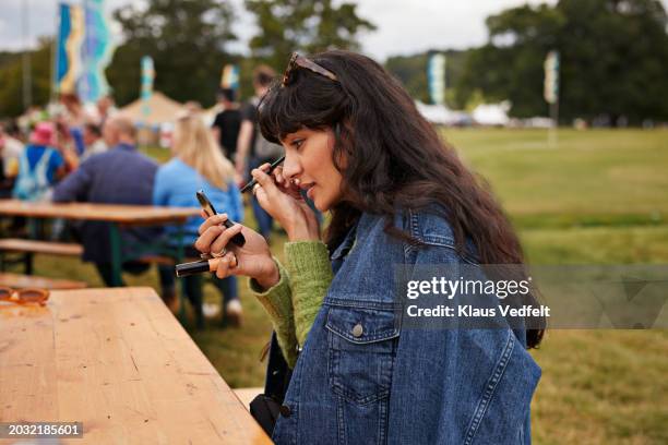 woman applying eyeliner while looking at hand mirror - eye liner photos et images de collection