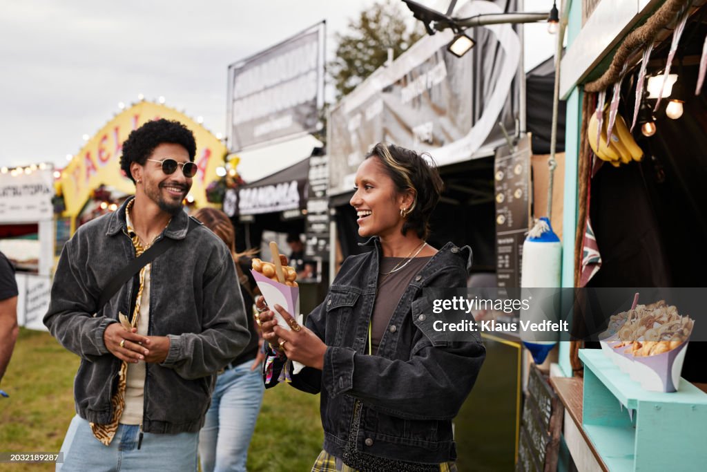 Smiling young woman holding dessert by friend