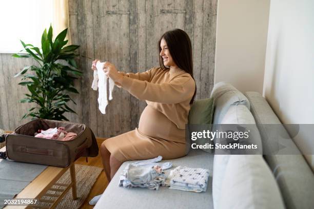 pregnant woman packing baby's clothes - babygro stock pictures, royalty-free photos & images