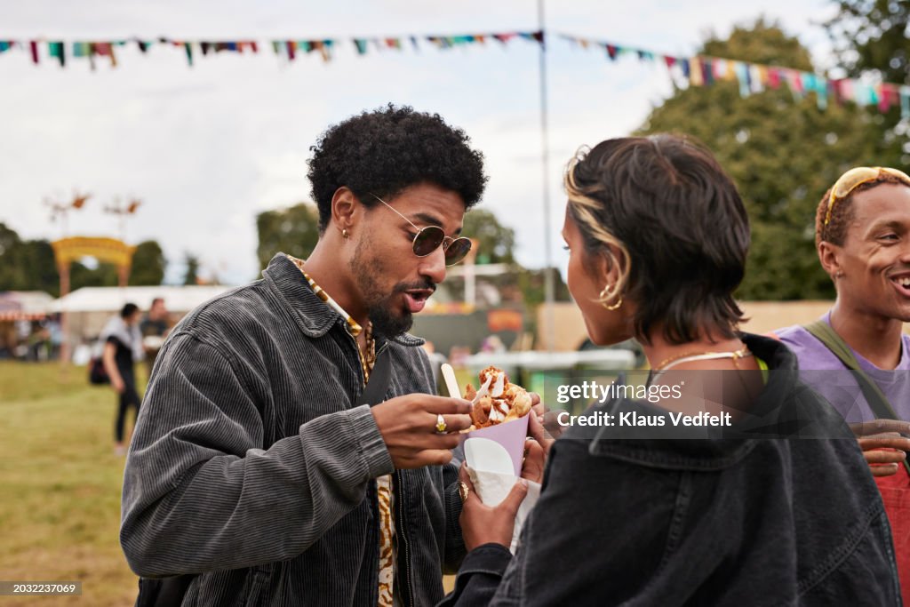 Young friends sharing dessert while eating together