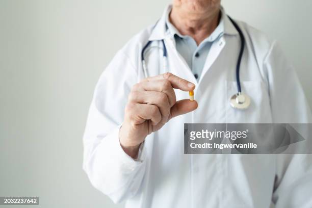 close-up of doctor in doctor's gown with stethoscope holding a pill - stethoscope pills stock pictures, royalty-free photos & images