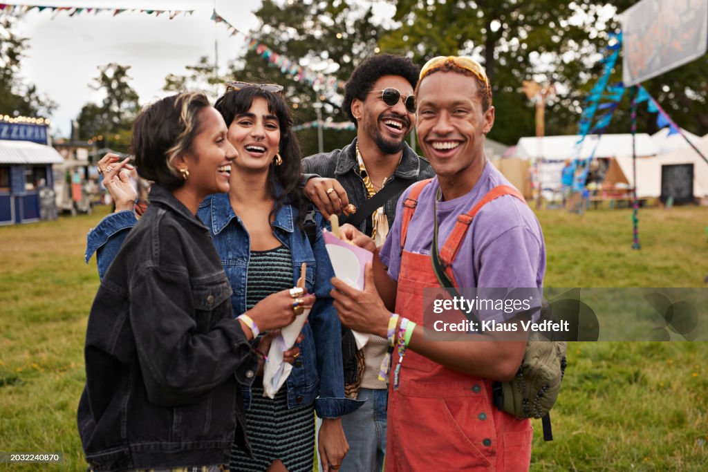 Happy multiracial friends sharing dessert at concert