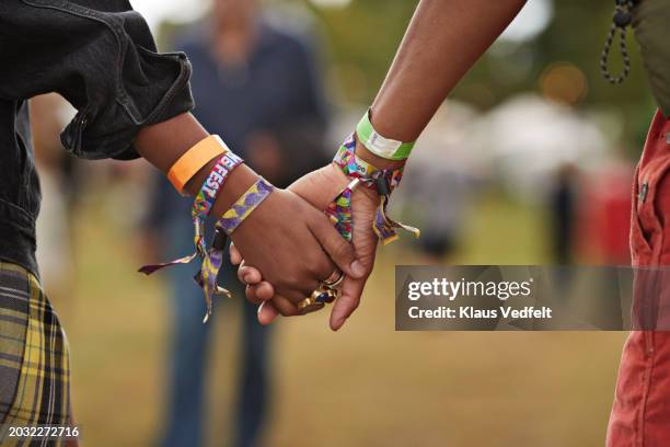 young couple with wristbands holding hands - festival de musique photos et images de collection