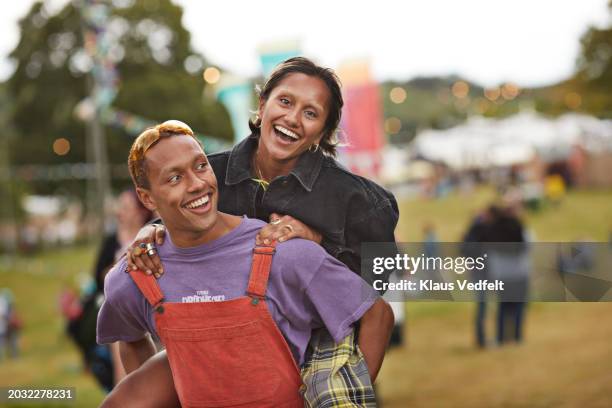 happy young woman enjoying piggyback on boyfriend - festival goer stock pictures, royalty-free photos & images