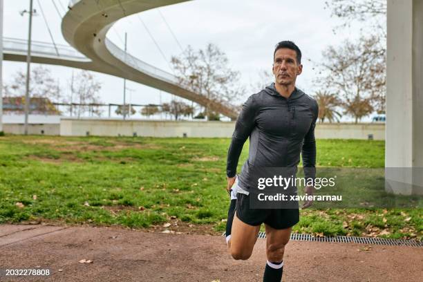 runner doing standing dynamic quad stretch, barcelona - sport determination stock pictures, royalty-free photos & images