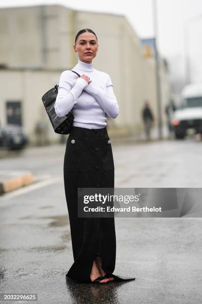 Sophia Roe wears a white tt top, a black leather bag, a black long slit skirt , outside Prada, during the Milan Fashion Week - Womenswear Fall/Winter...