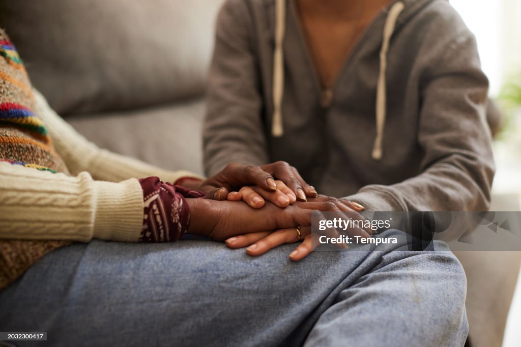 Daughter holding mother hands and comforting her