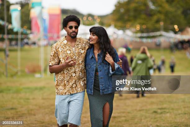 couple talking while walking together at festival - casal-de-verdade imagens e fotografias de stock