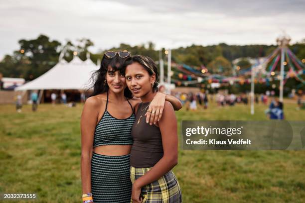 portrait of smiling woman with arm around female friend - festival field foto e immagini stock