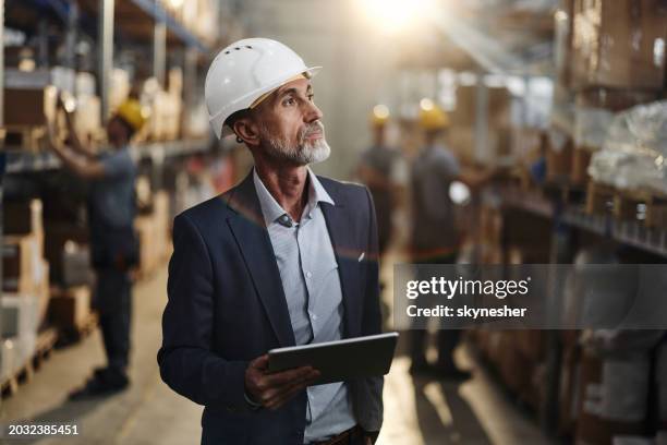 pensive mature manager using touchpad in storage room. - mestre de obras imagens e fotografias de stock