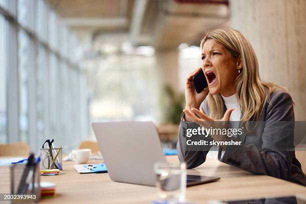 angry businesswoman talking on mobile phone in the office. - shouting phone stock pictures, royalty-free photos & images