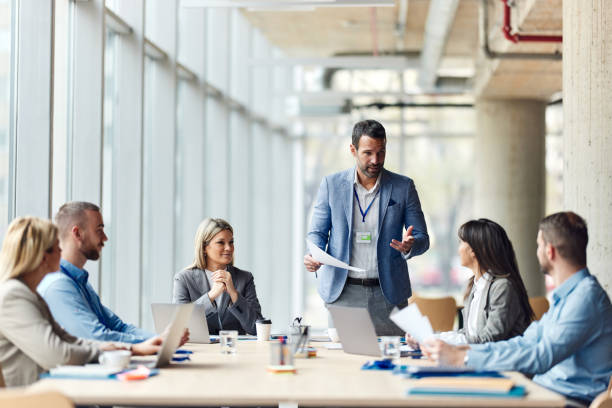 male leader talking to his team about plans on a meeting in the office. - communication stock pictures, royalty-free photos & images