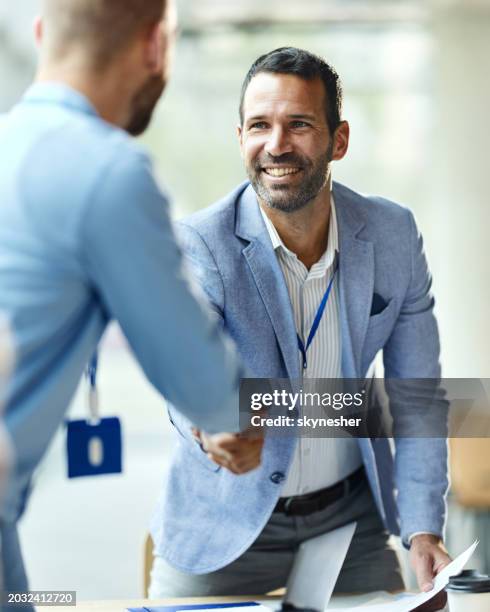 happy businessman greeting his colleague on a meeting in the office. - people say hello stock pictures, royalty-free photos & images