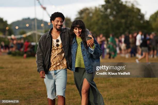 happy young man walking with arm around girlfriend - music festival field stock pictures, royalty-free photos & images