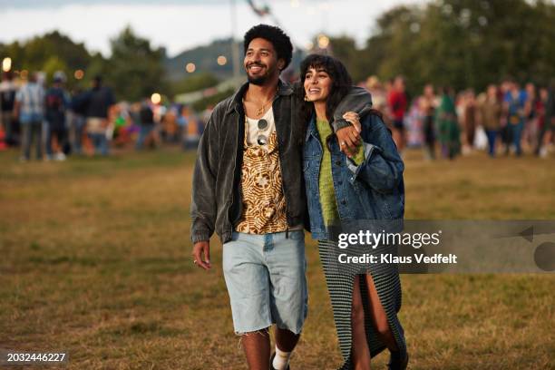 happy young couple looking away while walking at park - couple concert stock pictures, royalty-free photos & images