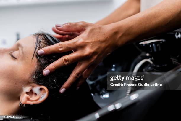 close-up of a hairdresser washing the customer's hair on a hair salon - beauty spa stockfoto's en -beelden