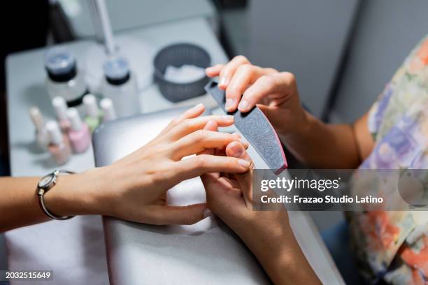 close-up of a manicurist sanding customer's nails in a beauty spa - manicureset stockfoto's en -beelden