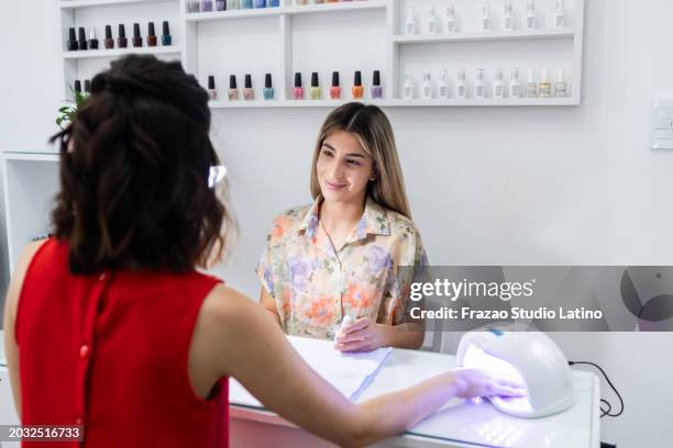 young manicurist doing customer's nails in a beauty spa - nail salon stock pictures, royalty-free photos & images