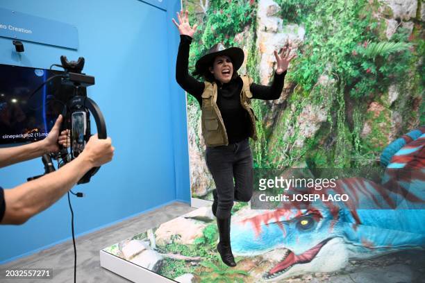 Woman jumps with a virtual image in background on the stand of Taiwanese consumer electronics company HTC at the Mobile World Congress , the telecom...