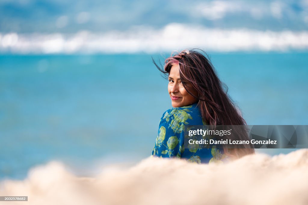 Woman turning to smile at the camera sitting on the beach