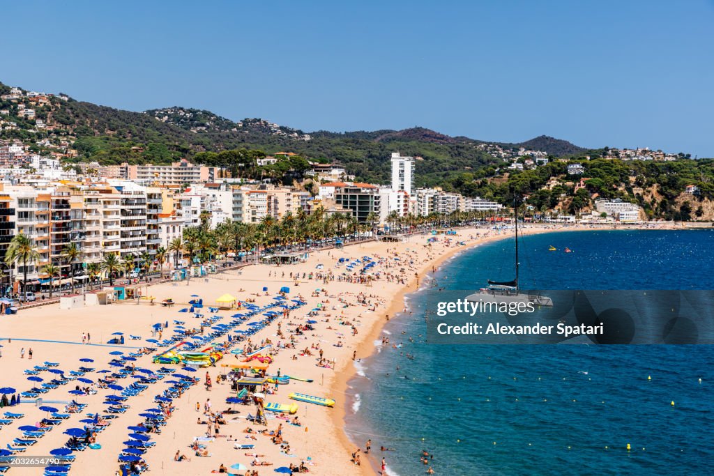 Beach with tourists in Lloret de Mar on a sunny summer day, Costa Brava, Spain