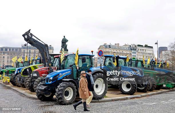 Couple walks past parked tractors of French farmers from the rural coordination agricultural union ahead of the opening of the 60th International...