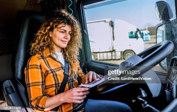 lkw-fahrerin prüft die lieferliste - lkw kabine stock-fotos und bilder