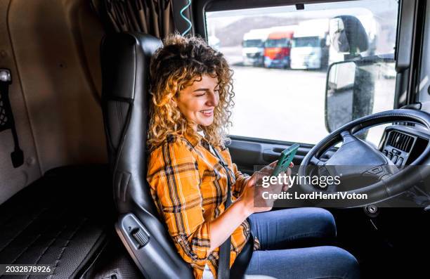 female truck driver checking smartphone - truck cockpit stock pictures, royalty-free photos & images