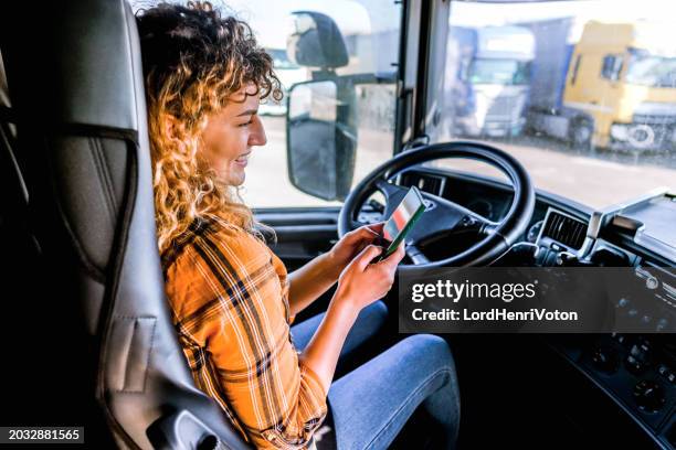 female truck driver checking smartphone - truck cockpit stock pictures, royalty-free photos & images