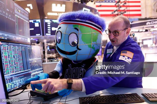 Harlem Globetrotter mascot Globey watches as trader Pete Giacchi works on the floor of the New York Stock Exchange during morning trading on February...