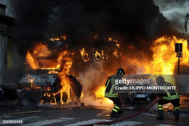 Firemen extinguish a car set on fire at Piazza del Popolo after clashes with youths during a protest to demand a change of government as parliament...