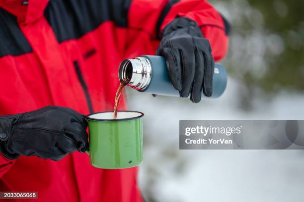 close-up of hiker pouring hot drink from thermos into travel mug - drinks flask stock pictures, royalty-free photos & images