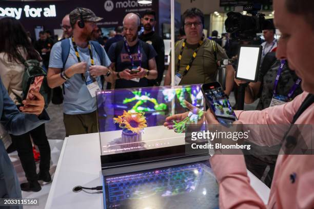 An attendee films a concept ThinkBook laptop computer featuring a transparent display at the Lenovo Group Ltd. Booth on the opening day of the Mobile...