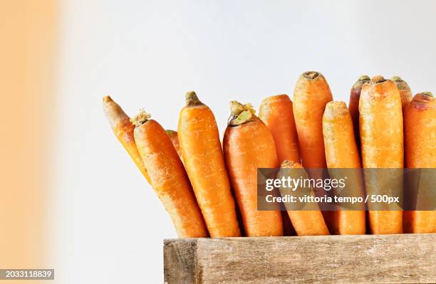 close-up of carrots in crate against white background - carote stock-fotos und bilder