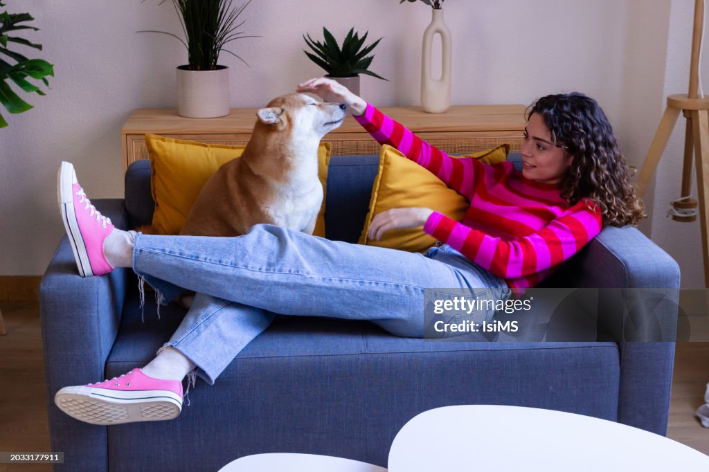 Woman relaxing on couch with playful dog