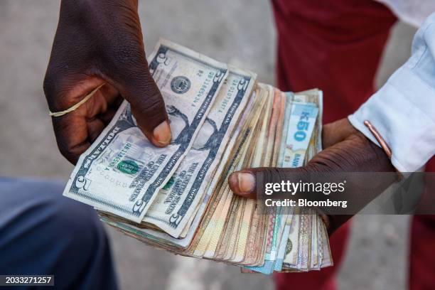 Street currency dealer counts US dollars and Zambian kwacha banknotes at a bus station in Lusaka, Zambia, on Friday, Feb. 23, 2024....