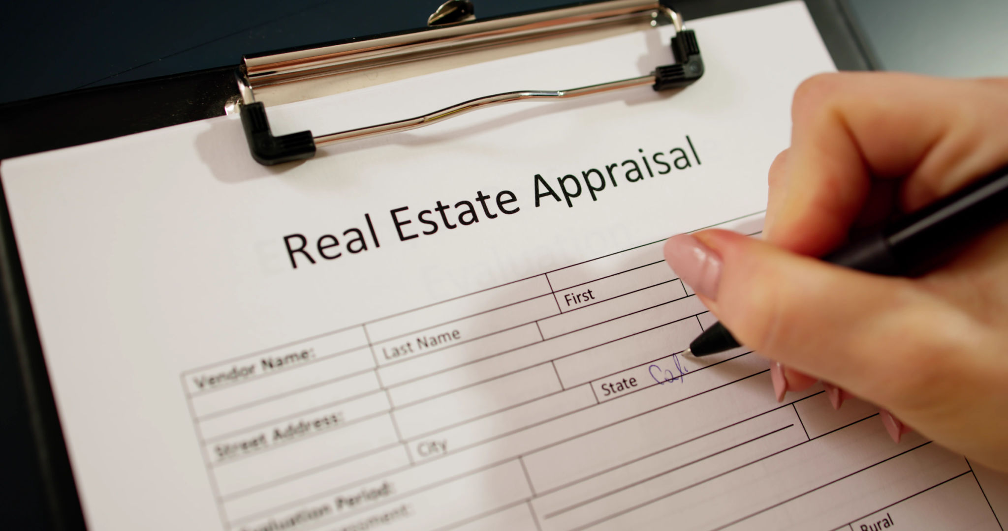 Close-up Of A Woman's Hand Filling Real Estate Appraisal Form Close-up Of A Woman's Hand Filling Real Estate Appraisal Form